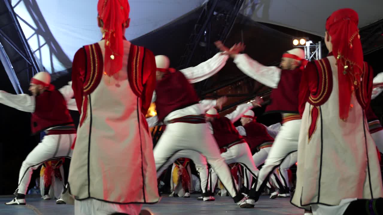 Men dressed in Albanian folk style dancing on the stage of international festival