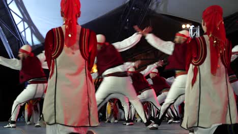 men dressed in albanian folk style dancing on the stage of international festival