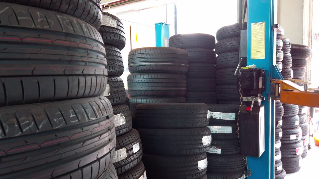 Panning view of multiple black tires stacked neatly inside repair garage