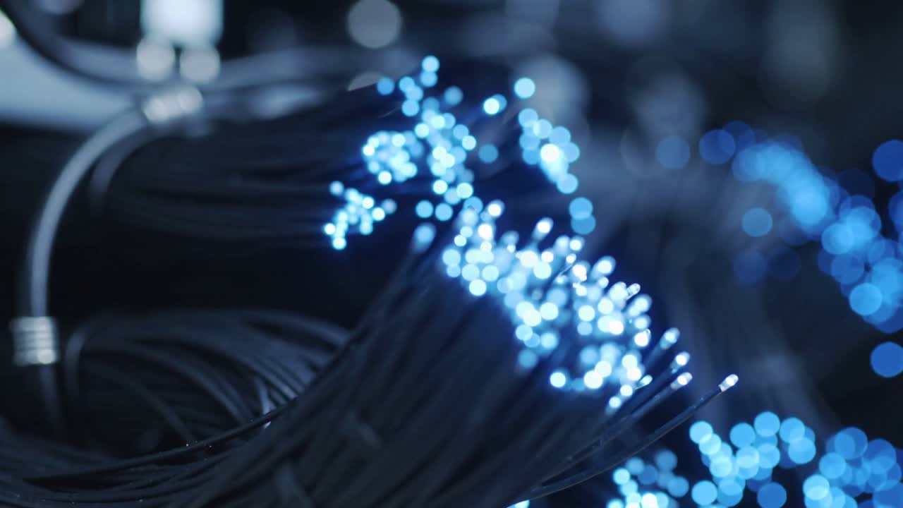 Pulling camera closer, foreground fiber bundle showing brightening blue tips in rack, with wraps