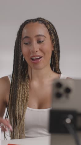 joven grabando belleza maquillaje revisión o tutorial para lápiz labial en teléfono móvil para cargar en el canal de redes sociales 1