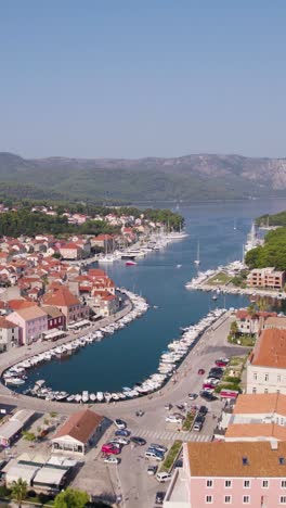 aerial view of stari grad harbor, hvar island, croatia, showcasing boats, traditional buildings, and mountains. vertical video