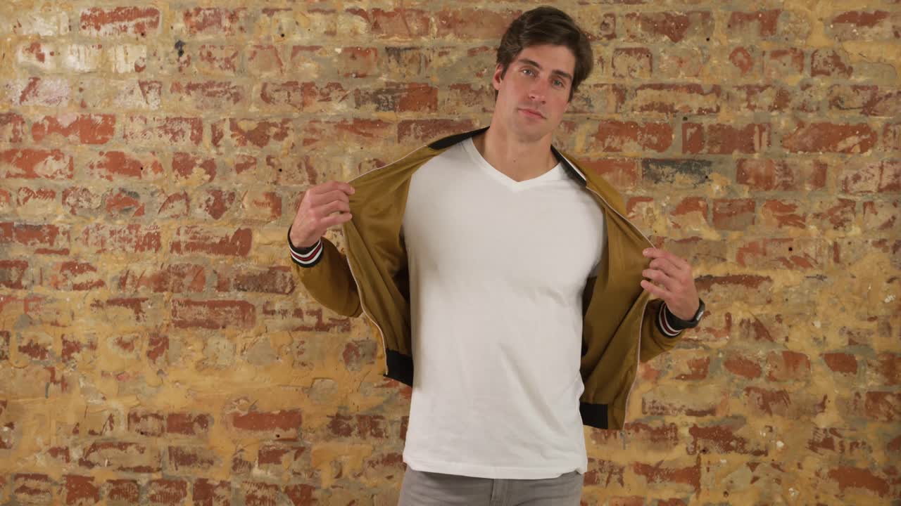 hombre caucásico mostrando su atuendo en una pared de ladrillo