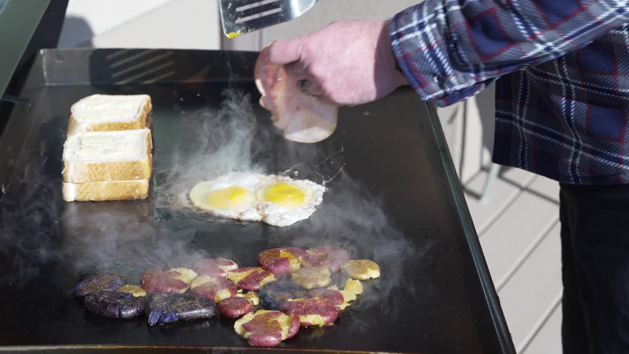 Adding ham to the frying eggs to make a Texas toast breakfast sandwich