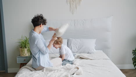 mother and son having fun with pillow fight