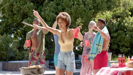 Portrait-of-happy-diverse-group-of-friends-having-barbecue-and-dancing-at-pool-party-in-summer