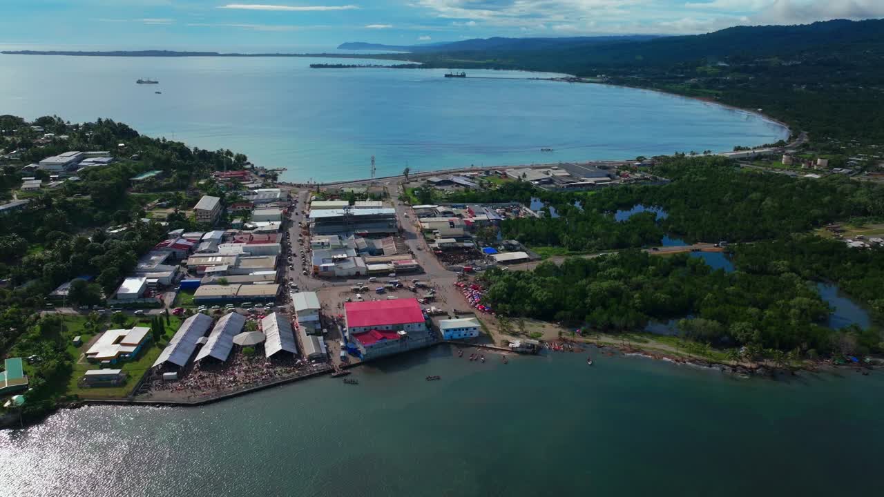 Wewak Bay harbour view Sundaun fish Market Wewak Hill buildings cars traffic people Boram road Papua New Guinea aerial drone downtown coastal town Dogreto Bay sunny morning blue sky forward pan up