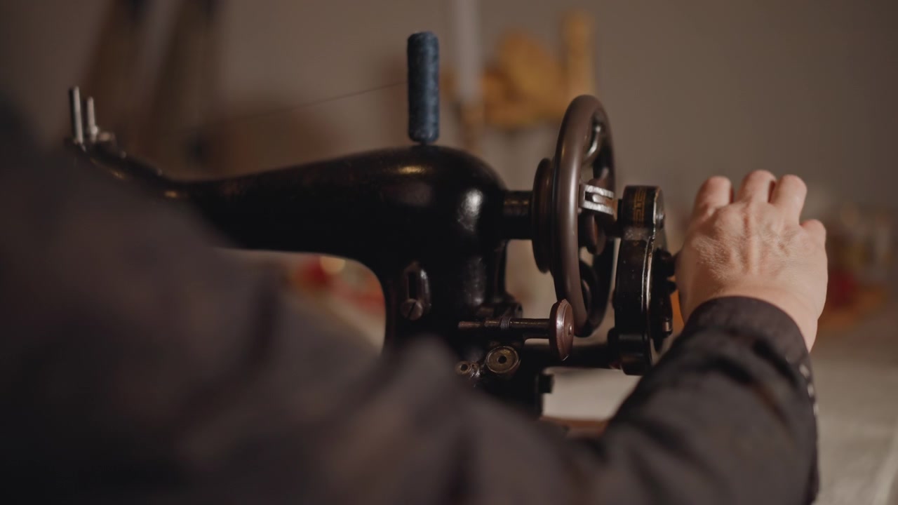 Restauro di macchine d'epoca. Una donna ripara un'antica macchina da cucire. Una sarta restaura con calma una macchina tessile retrò. Scena delicata in cui una donna restaura una vecchia macchina da cucire con cura e affetto.