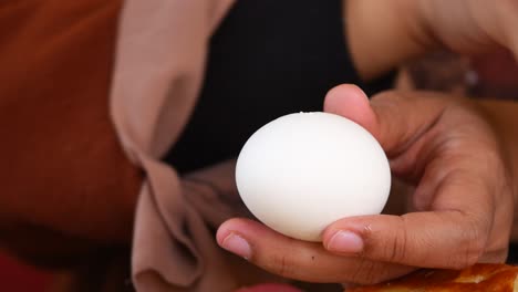 a woman's hands peeling a boiled egg for breakfast