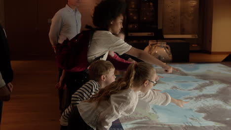 Pupils-On-School-Trip-To-Museum-Looking-At-Map-Shot-On-R3D