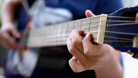 close up of a young boy playing blue acoustic guitar outside