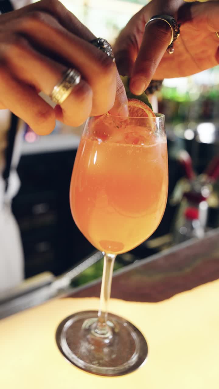 Barman che guarnisce un cocktail rinfrescante con arancia e basilico