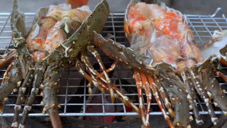 motion shot two open lobsters on traditional clay barbecue - thailand