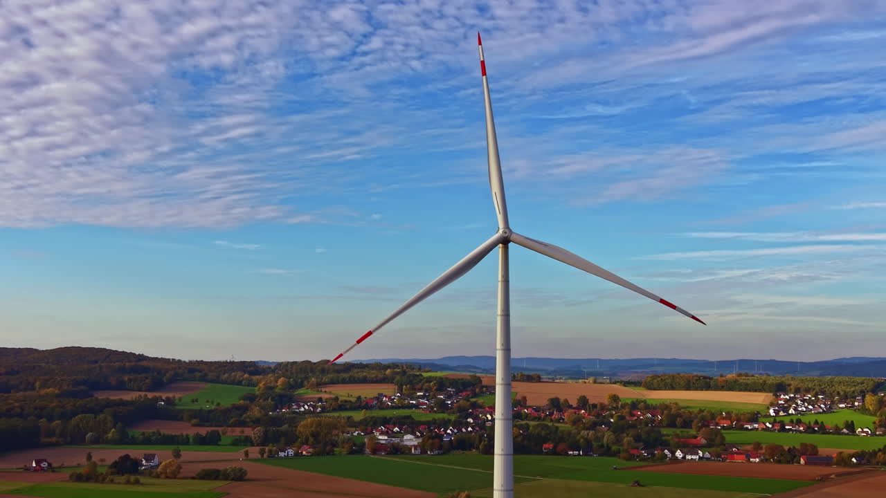 Imponenti turbine eoliche si ergono verso un cielo vivace in un sereno paesaggio rurale in una soleggiata giornata autunnale
