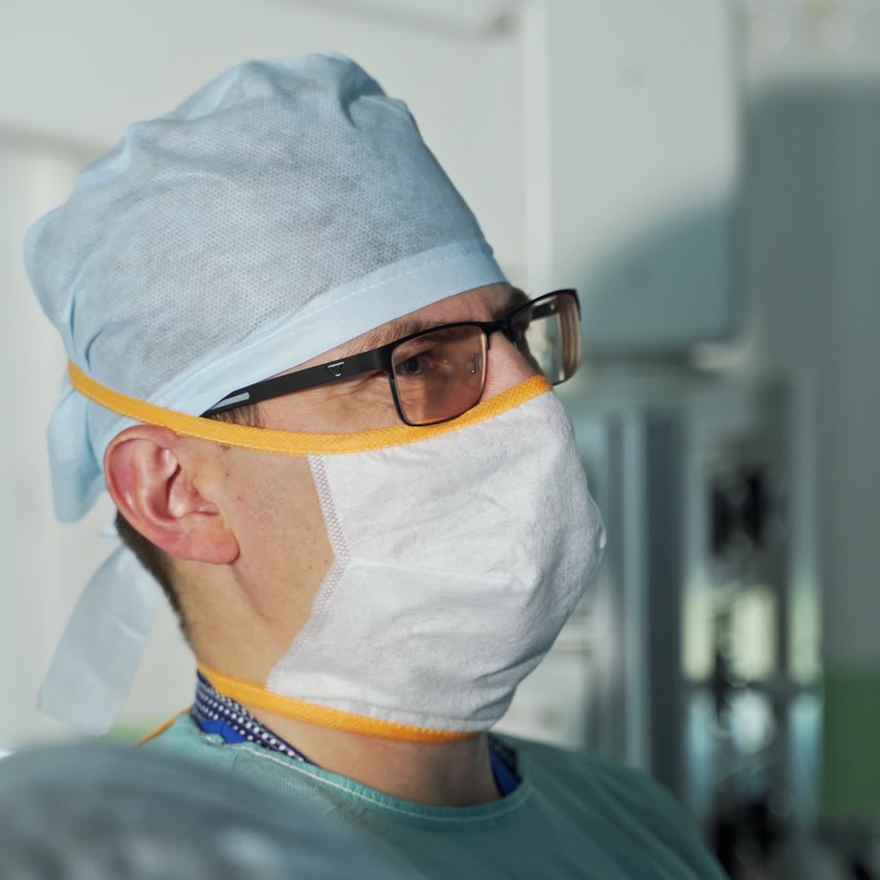 Focused concentrated look of a surgeon in glasses during operation. Portrait of a male doctor in surgery room