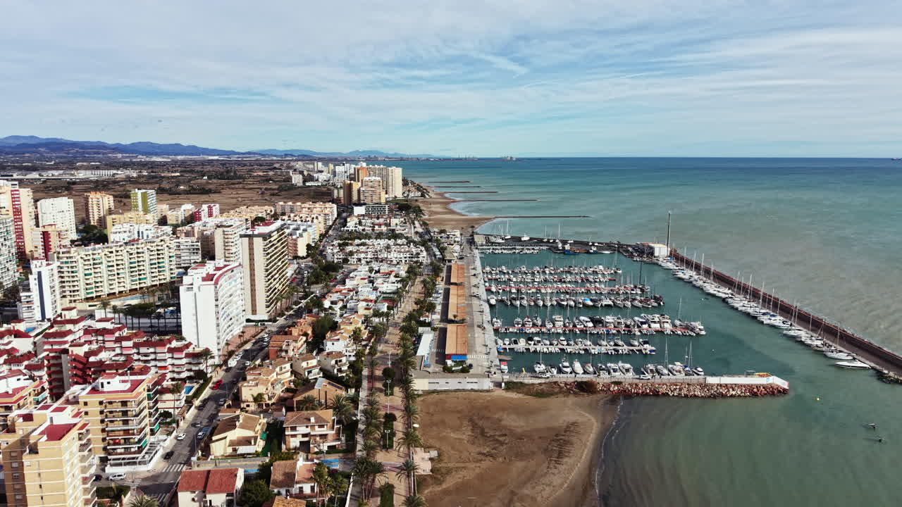 Vista di una costa con edifici, un porto turistico e l'oceano sullo sfondo in una giornata limpida in Spagna