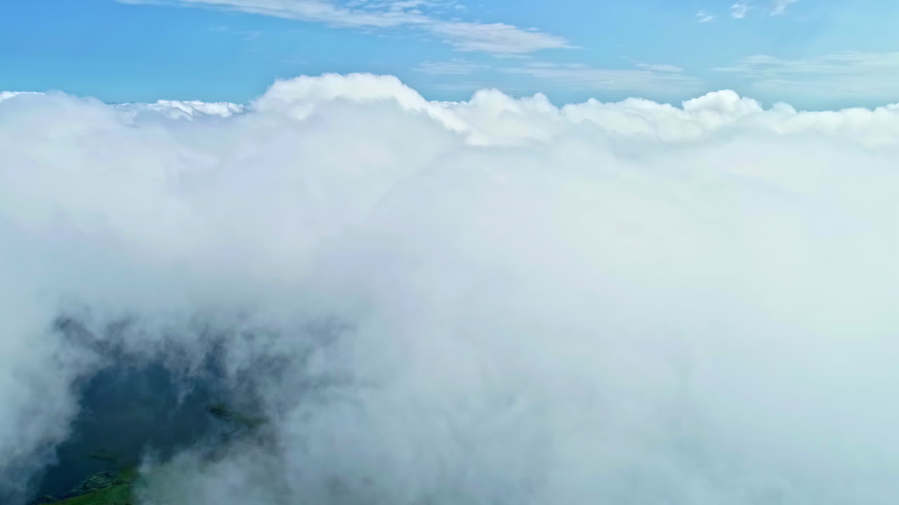 Flying above thick clouds with the peak on green meadows below