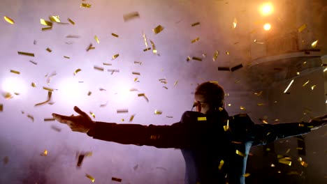 successful businessman with arms up celebrating his victory. celebrating success. low angle view of excited young businessman keeping arms raised and expressing positivity while stands on the stage in the background of the hall