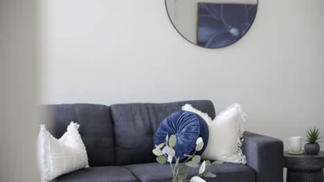 modern contemporary styled home dark couch navy blue and white cushions circle mirror coffee table with vase and stem