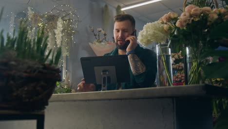 female florist talks by phone with customer and uses tablet