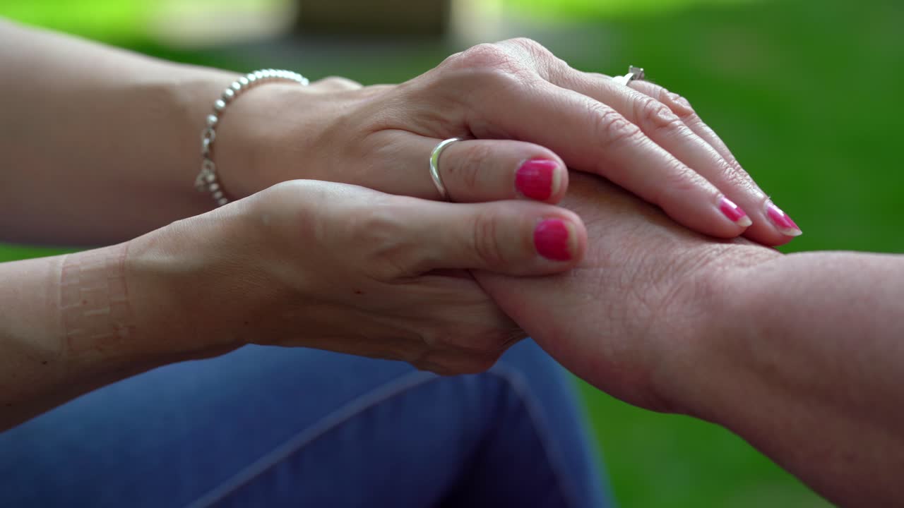 Hands of woman comforting and older lady outside grief distress