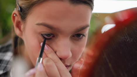 close-up view of young lady gently applying eye pencil to her eye, she focuses carefully as she enhances her eyes, with subtle precision and attention to detail in makeup routine