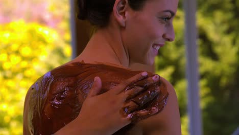 Smiling-woman-having-a-mud-treatment-applied-to-her-back