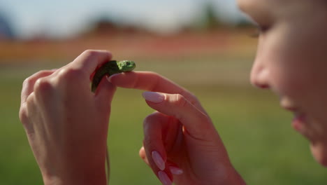 closeup green lizard in female hands outdoor. pretty girl face and little lizard