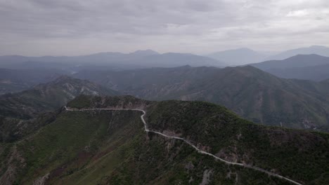 "golden-hour"-head-on-drone-video-moving-over-the-mountains-of-SH22-in-albania,-above-the-road-on-top-of-the-hill