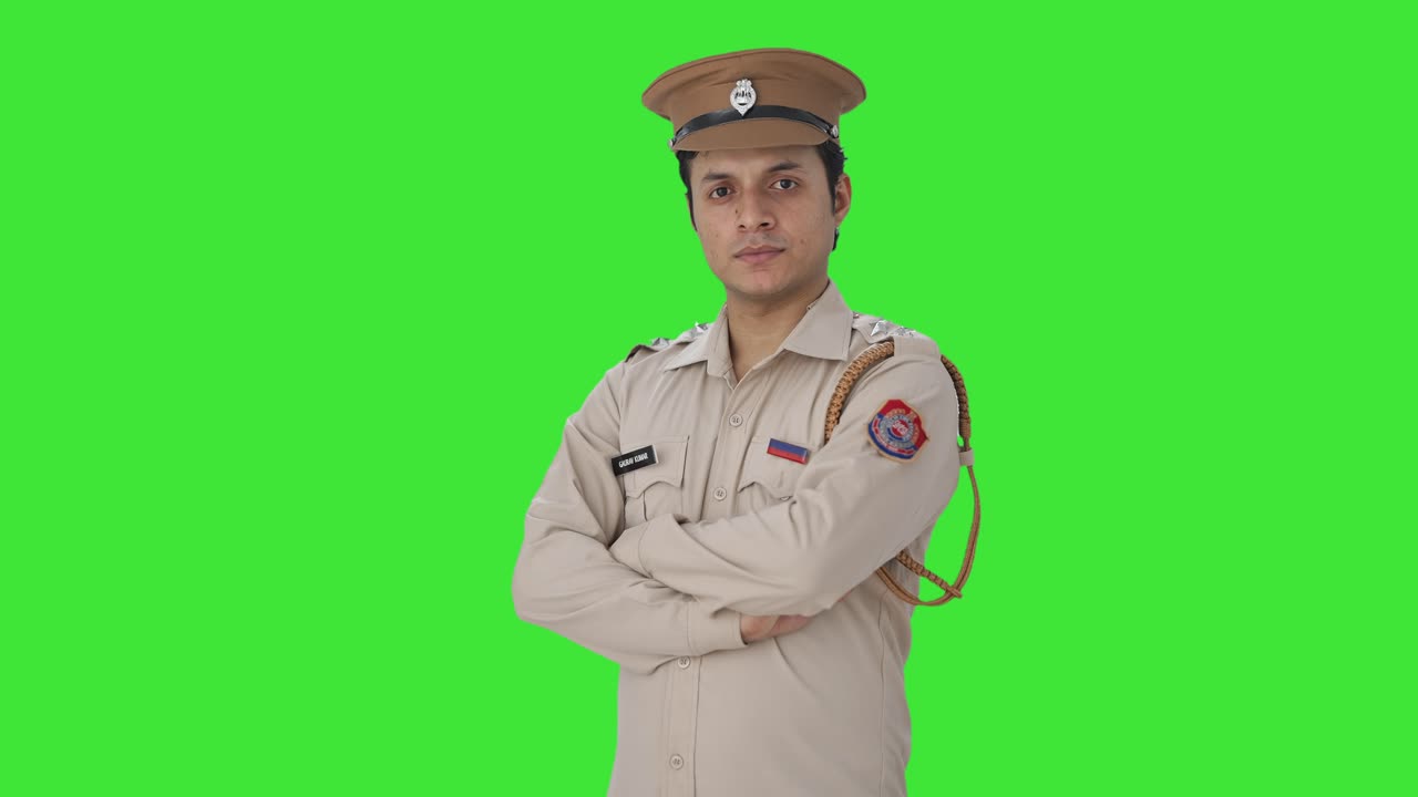 Ritratto di un agente di polizia indiano sicuro di sé in piedi con le braccia incrociate su sfondo Green screen