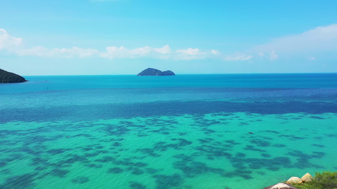 Beautiful seascape with blue turquoise sea full of coral reef patterns, washing cliffs on coastline of tropical islands under bright sky in Thailand