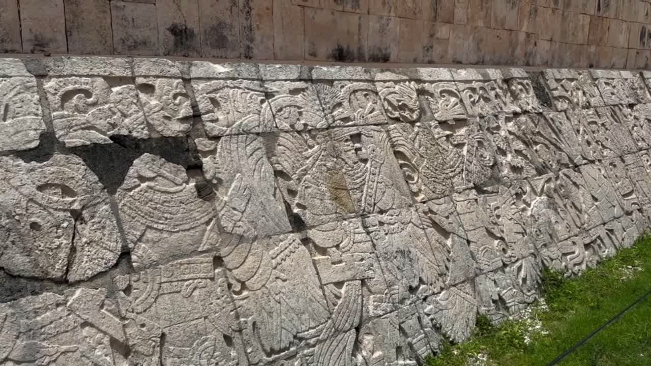 Handheld close-up panning shot of stone relief carvings at the Great Ball Court in Chichen Itza, Mexico. 4K