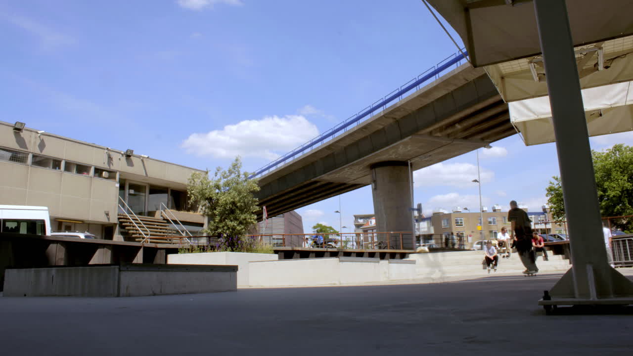 Open air skatepark beneath bridge in sunny urban setting