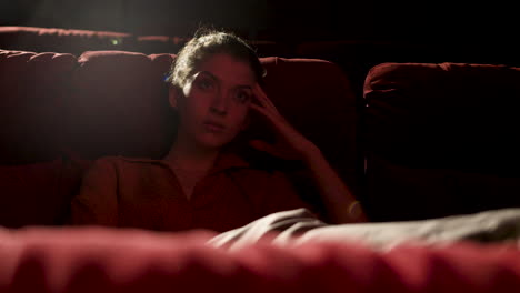 mujer rubia sentada en el cine viendo una película y mirando a la cámara