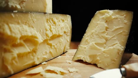 queso parmesano de cabeza dura media en tablero de madera, con cuchillos de parmesán de queso. tiro de diapositiva