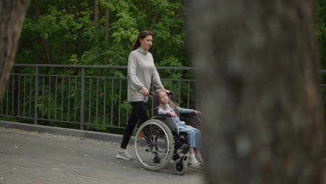 mom walks on pavement with daughter sleeping in wheelchair