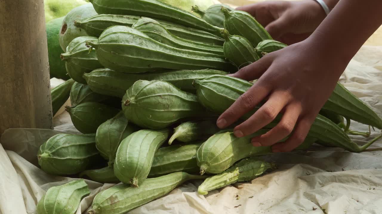 pila de calabaza de cresta cerca en el mercado local con la mano de la hembra separada y controlando la calidad de los alimentos, segregando la calabaza de cresta