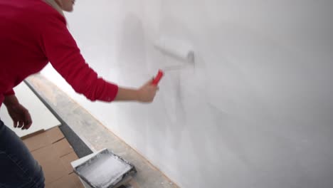 the-woman-painting-walls-with-roller-equipment-while-moving-in-apartment.-Renovating-new-house-and-improvement-concept