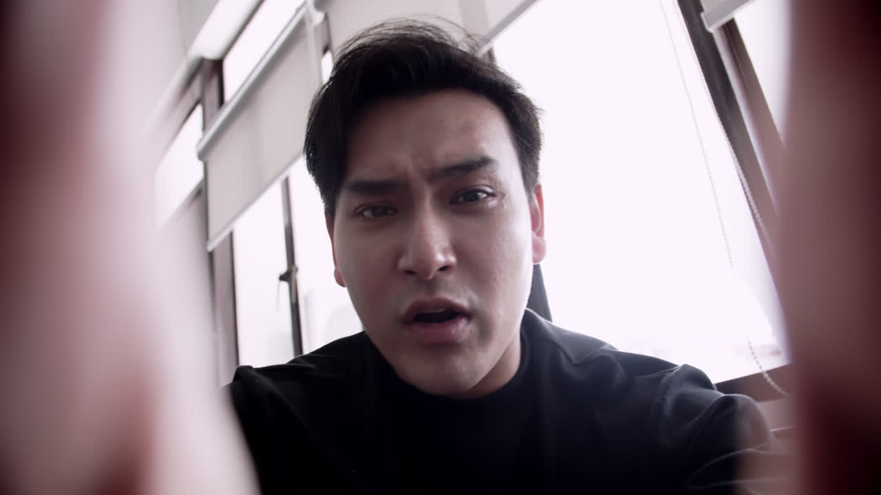 Phone POV of an Asian man looking anxious pouring out his heart to his friend about his problems. Sad, depressed, and disappointed mood.