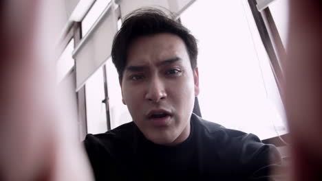 phone pov of an asian man looking anxious pouring out his heart to his friend about his problems. sad, depressed, and disappointed mood.