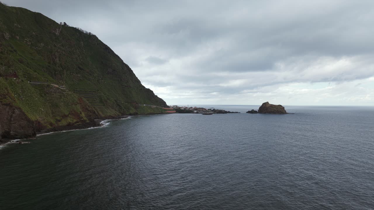 Drone flies through natural rock arch of Ilhéus da Ribeira da Janela, sea stack, coastline. Madeira, Portugal. Aerial forward