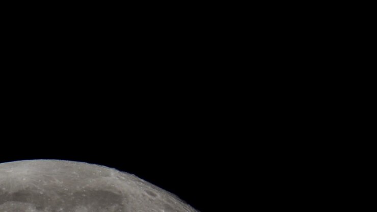 Um vídeo super telefoto da Lua Cheia gigante passando pelo céu noturno no espaço, filmado com um telescópio