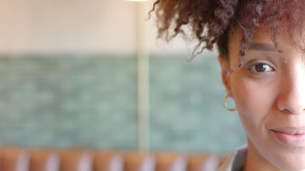 African woman reacting to offscreen joke, smiling in cafe with gold hoop earring, copy space