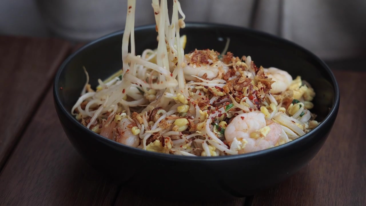 Seseorang Makan Mi Pad Thai Lezat dengan Udang dan Sumpit