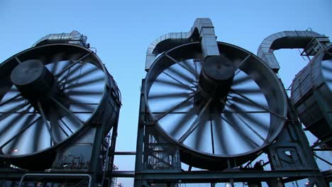 large industrial fans spin rapidly in a manufacturing facility at dawn. the scene captures the early morning light illuminating the machinery, showcasing the operational efficiency of the plant.