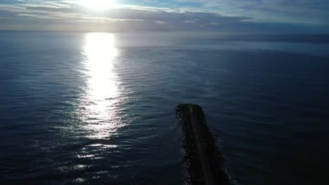 amanecer en la vía marítima de la costa dorada, sol en las nubes brillando sobre el agua