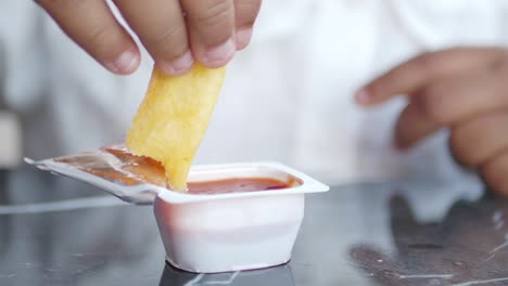 person dipping french fries in ketchup