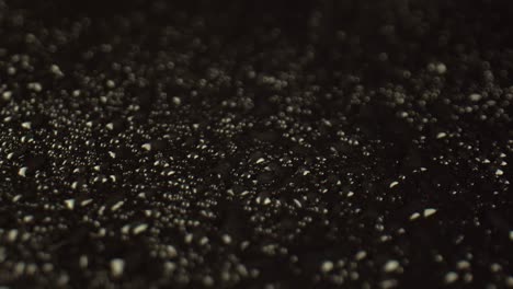 transparent drops of water cover the black surface of the table, a close-up. a scattering of beautiful raindrops on a dark background.