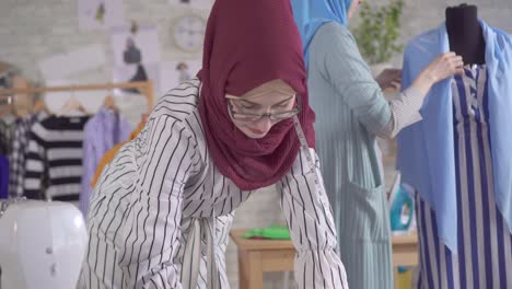 young muslim women fashion designers in national headscarves at work in a modern studio close up