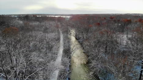 aerial panoramic view of rushing creek during sunrise in snow-covered forest in michigan